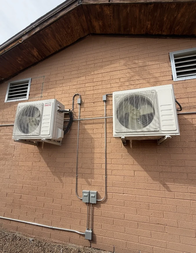 Two Mitsubishi mini-split condensers mounted on an exterior wall
